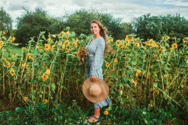 Ayçiçekleri arasında tarlada yürüyün