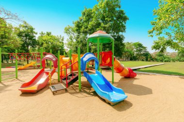 Yeşil ağaçlarla çevrili parktaki renkli çocuklar oyun parkı aktiviteleri