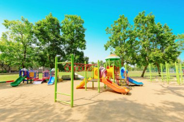 Yeşil ağaçlarla çevrili parktaki renkli çocuklar oyun parkı aktiviteleri
