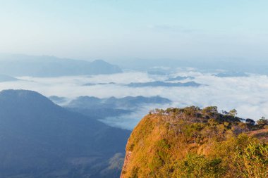 Gün doğumunda sabah sisi ile birlikte dağ manzarası.