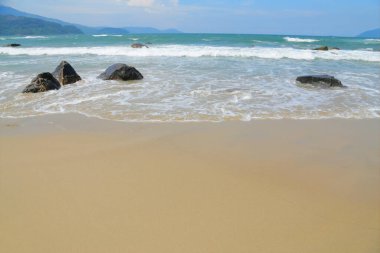 Deniz dalgalarıyla kumsal Gökyüzünün mavi olduğu gün