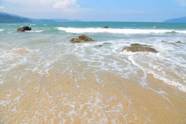 Deniz dalgalarıyla kumsal Gökyüzünün mavi olduğu gün