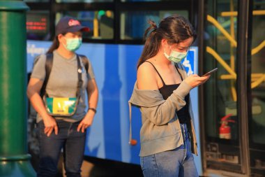 Bangkok - Tayland, 29 Şubat 2020: Tıbbi maske takan insanlar tozu ve mikrobu önler. Akşam güneş ışığı vardı.