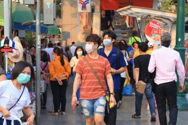 Bangkok - Tayland, 29 Şubat 2020: Tıbbi maske takan insanlar tozu ve mikrobu önler. Akşam güneş ışığı vardı.