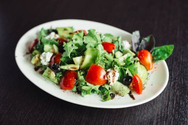 Salata yeşillikleri ve peynir beyaz bir tabakta