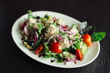 Beyaz bir tabak üzerinde yeşillik, peynir ve soğan salatası