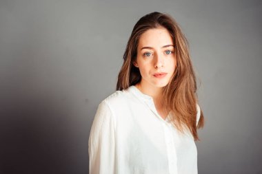 Gülümseyen kız, gri arka planda elleri yüzüne yakın, kapat. Makyajsız, rötuşsuz.