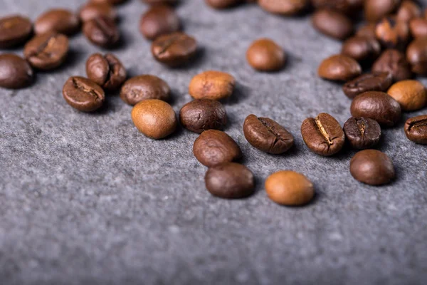 Roasted coffee beans on a stone background. Coffee beans texture. Coffee in beans on dark background. Food background of coffee beans. Abstract background texture.