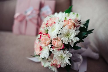 Gül buketi ve kasımpatı pembe sertifikaların arka planında pudra gibi bir kanepede