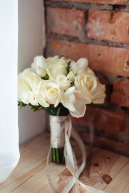 Beyaz güllerin düğün buketi tuğla duvar arkasında kırsal bir tarzda