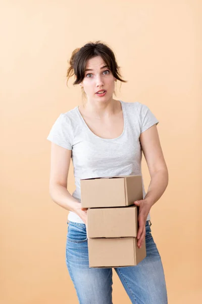 Surprised girl holds boxes in her hands on a beige background. Good delivery service