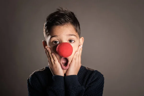 Niño Con Una Nariz Payaso Sobre Fondo Gris —  Fotos de Stock