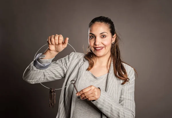 businesswoman holding old keys on a gray background