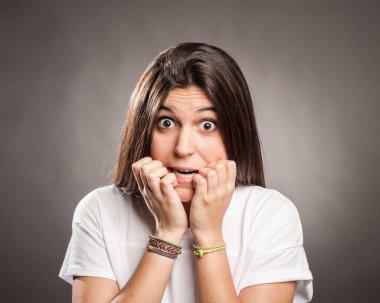 Gri arka planda korkmuş genç bir kadının portresi.