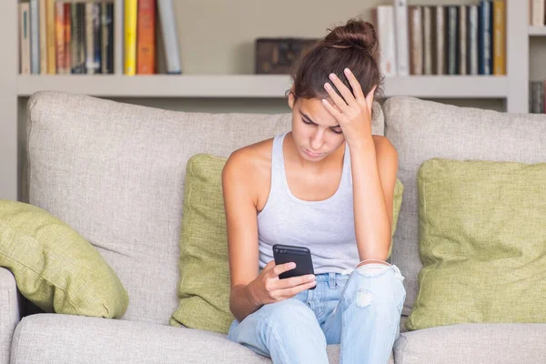 Marah Gadis Muda Membaca Pesan Dalam Ponsel Pintar Duduk Sofa — Stok Foto