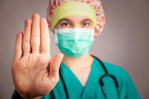 doctor wearing face mask showing stop sign with her hand. Coronavirus concept