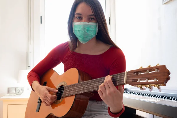 女学生戴着面具 在家里弹吉他 — 图库照片