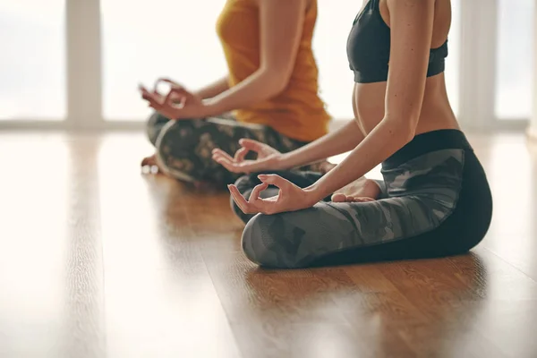 Two woman doing yoga flow in studio