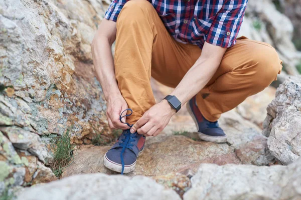 Man ties up shoe laces while hiking