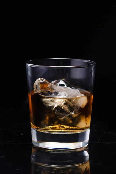 Um copo com uísque e gelo sobre um fundo — Fotografia de Stock