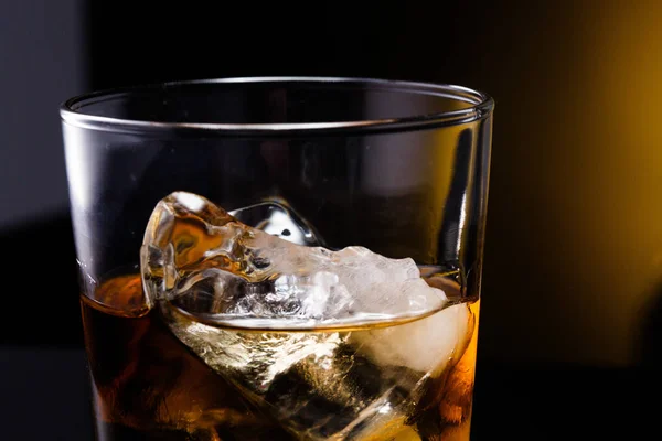Um copo com uísque e gelo sobre um fundo — Fotografia de Stock