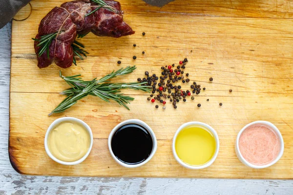 Cut off beef with herbs and sauces on a wooden board. — Stock Photo, Image