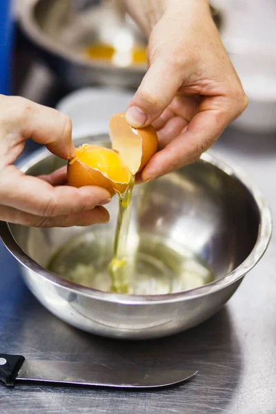 The cook breaks the egg in a steel bowl — Stock Photo, Image