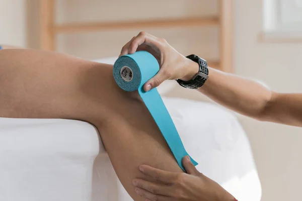 Fizyoterapist vücuduna bantla kineso koyar. Kinesiyoloji taping, yakın çekim 