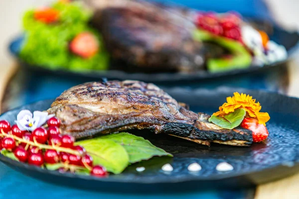Siyah plaka üzerinde taze salata ile ızgara biftek yakın. Yiyecekler ızgarada pişirilir. Izgara ve barbekü konsepti