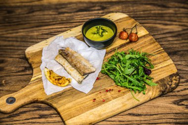 Ahşap masada servis edilen taze sebzeli ızgara balık filetosu. Restorandaki yemek. Yemek tasarımı ve restoran yemeği. 