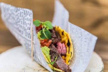 Tahta bir tabakta et, salsa ve sebzeli Meksika tacoları. Restorandaki yemek. Yemek tasarımı ve restoran yemeği.