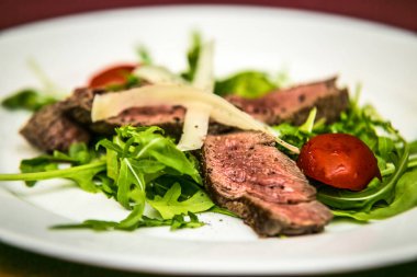 Peynirli domuz eti ve tabakta sebze. Restorandaki yemek. Yemek tasarımı ve restoran yemeği.