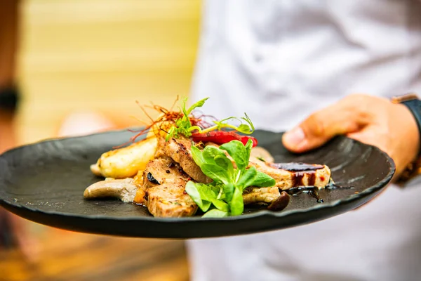Yemek taşıyan bir garsonun eline yakın çekim. Restorandaki yemek. Yemek tasarımı ve restoran yemeği. 