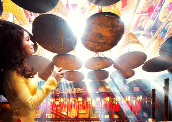 Chinese lady in gold cheongsam dress in chinese temple, Hong kong, China