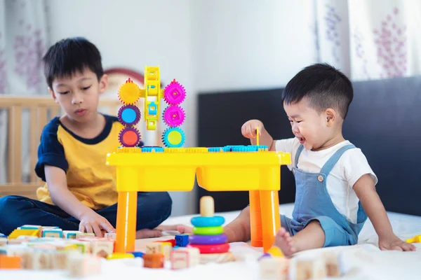 哥哥和一个微笑的男孩在床上玩玩具聚集 这个模仿可以用于孩子 家庭和玩具的概念 — 图库照片