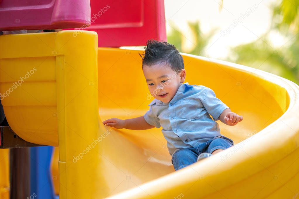 Asian boy smile and play slider in playground in a park
