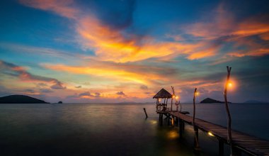 Günbatımı gökyüzü ile Koh Nak 'taki ağaçlı köprü.