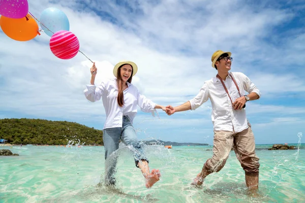 Asiática pareja correr y feliz en Pattaya playa con globo en la mano —  Fotos de Stock