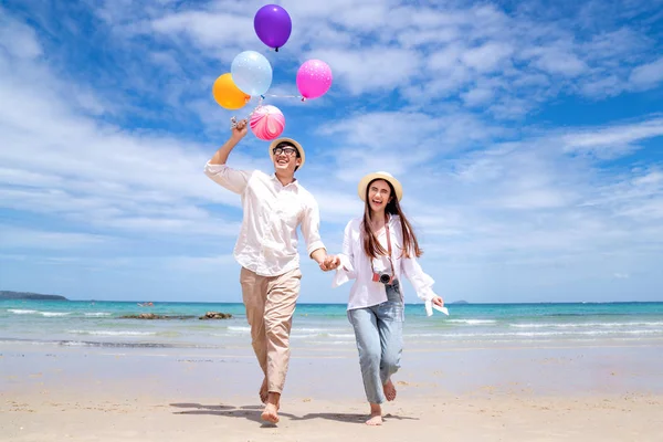 Asiático casal correr e feliz na praia de Pattaya com balão na mão — Fotografia de Stock