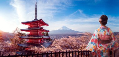 Geleneksel kimonolu Japon kız Sakura parkında yürüyor.