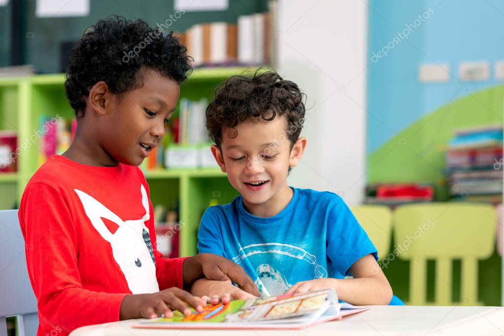 Student in international preschool reading a magazine book toget