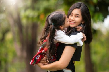 Asyalı anne ve bebeği parkta öpüşüp eğleniyorlar.