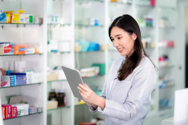 Asian Pharmacist girl use tablet pad computador para verificar o estoque de — Fotografia de Stock