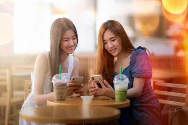 Két Boldog Gyönyörű Fiatal Ázsiai Asztalnál Beszélgetnek Mobiltelefonnal Játszanak Kávézóban Stock Fotó