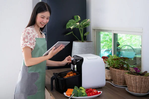 アジアの妻は 今日の夕食のためのフライドチキンを調理するための無機質な空気フライヤーマシンを作った この画像は キッチンや技術の概念に使用することができます — ストック写真