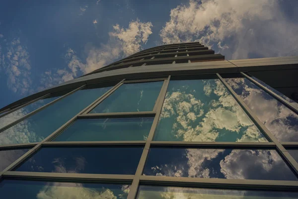 A big building with big glasses below a blue,cloudy summer sky