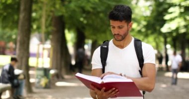 Öğrenci kitap okuma Park'ta yürüyordunuz gülümseyen 