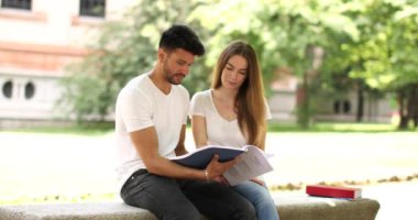 İki öğrenci açık hava bankında birlikte ders çalışıyor.