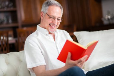 Adam evde kitap okuyor. 