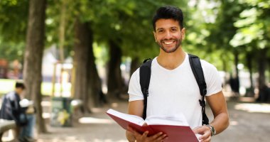 Yakışıklı genç bir üniversite avluda kitap okumak